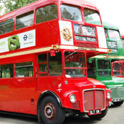 a row of red double decker buses parked next to each other