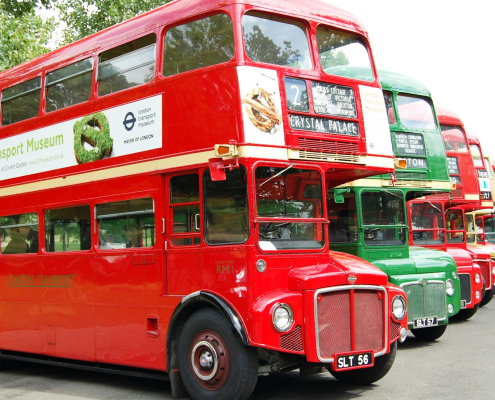 a row of red double decker buses parked next to each other